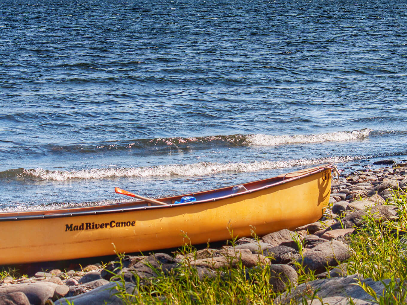 Una canoa amarilla en la orilla de un lago azul demuestra el contraste de color en la fotografía.